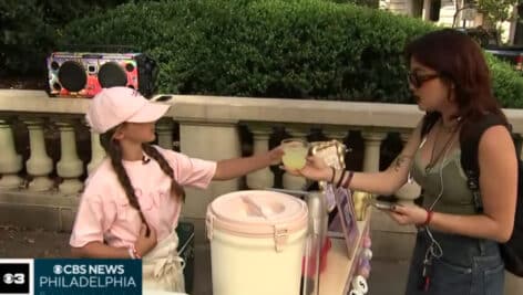 Elena Flores (left) hands a cup of lemonade to customer (right).