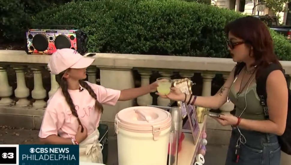 Elena Flores (left) hands a cup of lemonade to customer (right).