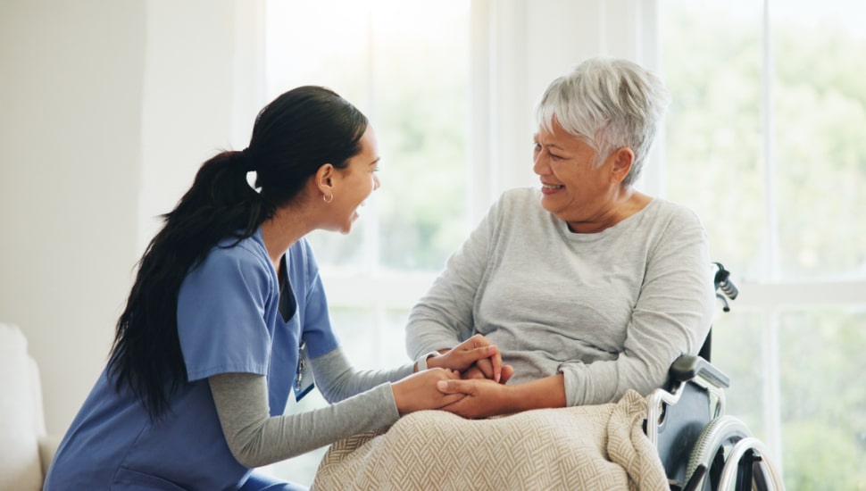 An elderly woman in a wheelchair being cared for.