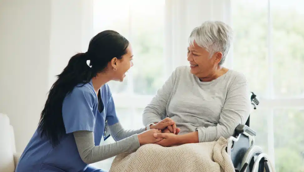 An elderly woman in a wheelchair being cared for.