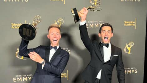 Justin Paul and Benj Pasek smiling and holding up their Emmys proudly.