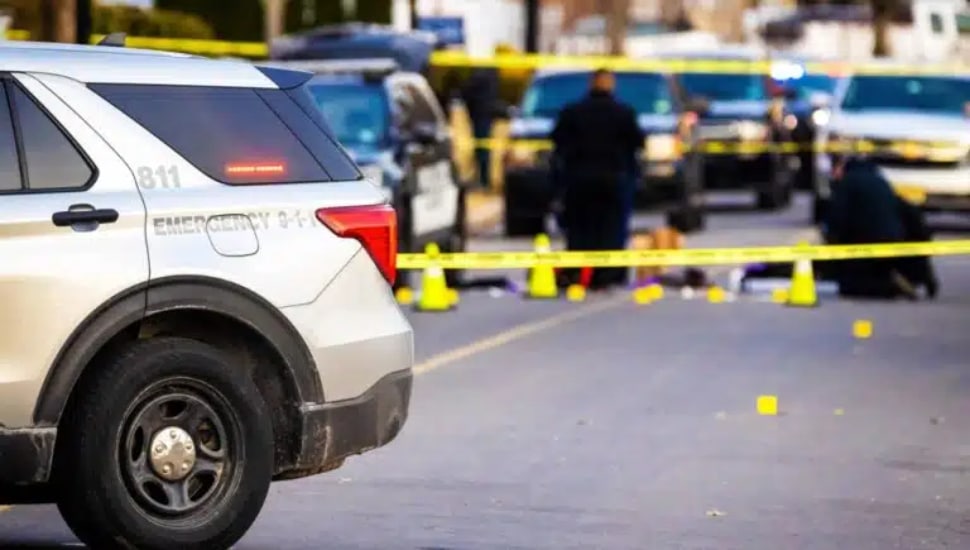 Police car with emergency lights on road with caution tape.