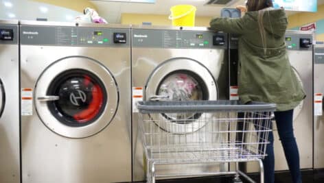 A woman washing clothes inside a laundromat.