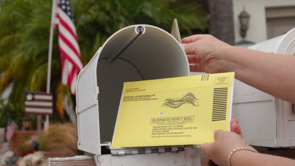 Woman puts US mail-in ballot into mailbox.