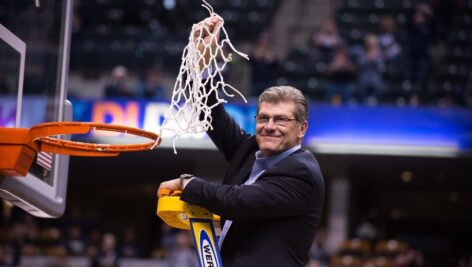 Geno Auriemma cuts the basketball net after a victory.