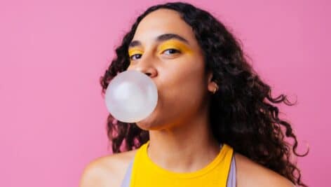 A woman blowing a bubble with her gum.