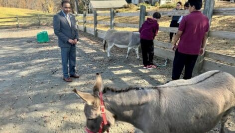 Students and principal at a farm with a horse.