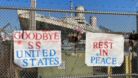 SS United States behind a gate with farewell signs.