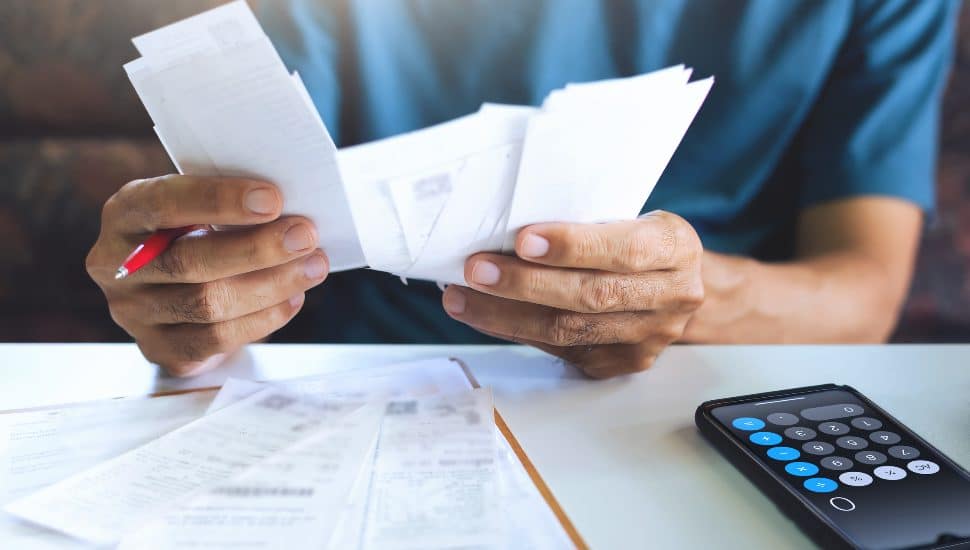 stressed person using calculator for high tax bills.