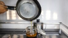 Person pouring the used cooking oil into the old oil container.