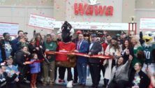 Wawa store general manager Lauryn Hughes cuts the ribbon on the latest Wawa in Ridley Township as a crowd gathers around.