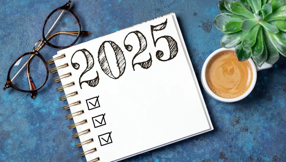 New Year's resolutions 2025 on desk with notebook, coffee cup, on table.