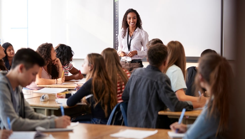 A female teacher in a classroom filled with students.
