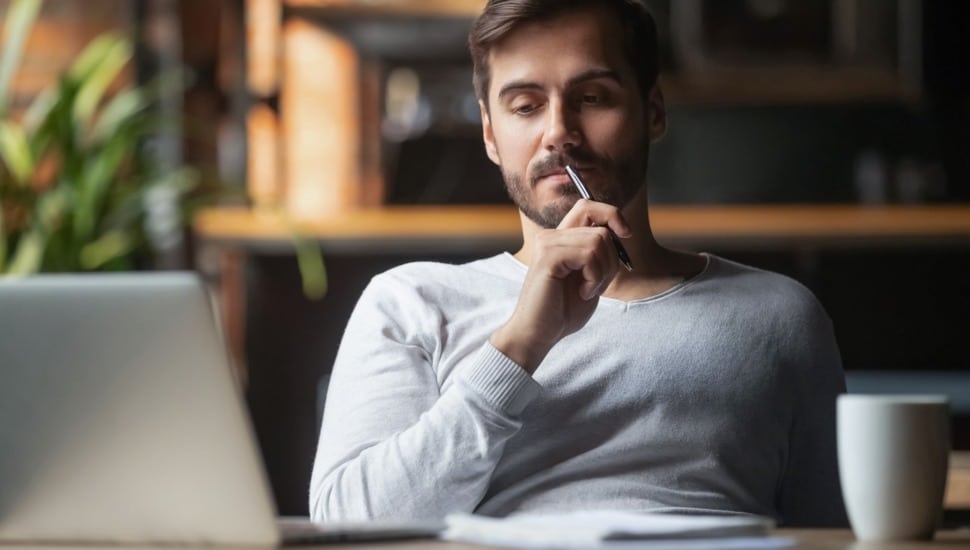 Pensive male thinking over problem solution working on laptop.