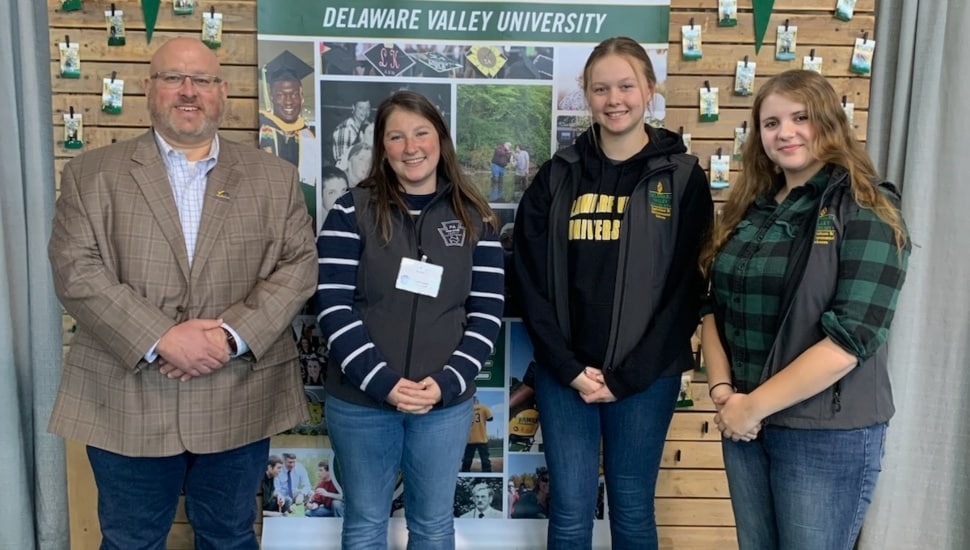 College students and professor pose for a group photo at a farm show.