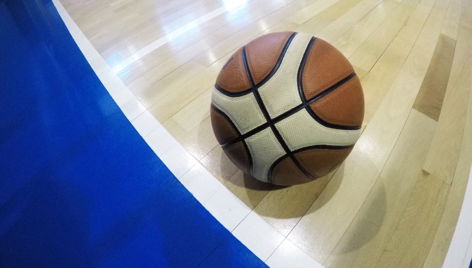 A basketball on the court near the out-of-bounds line.