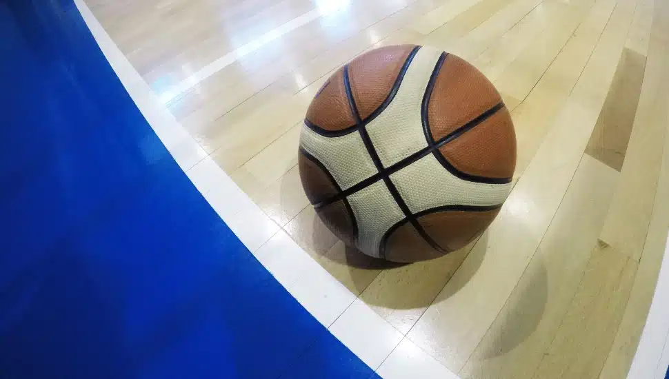 A basketball on the court near the out-of-bounds line.