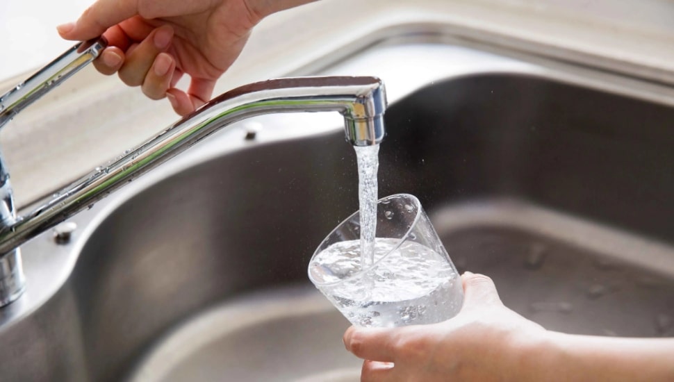 Filling a glass with water from a faucet.