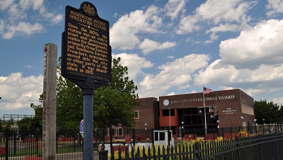 Washington Avenue Immigration Station historical marker with the United States Coast Guard in the background.
