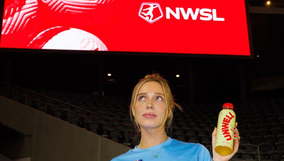 Alex Cooper poses below a National Women’s Soccer League banner