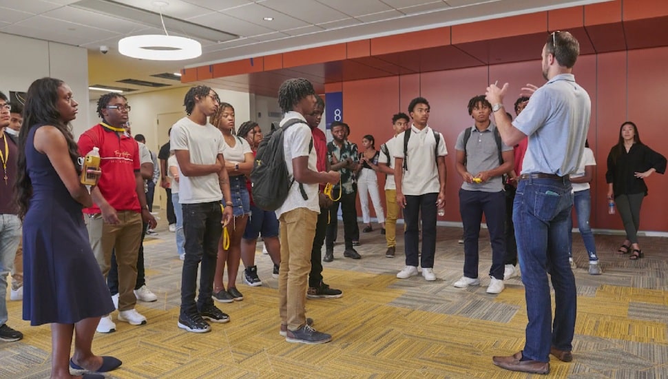 Students standing around listening to instructor.