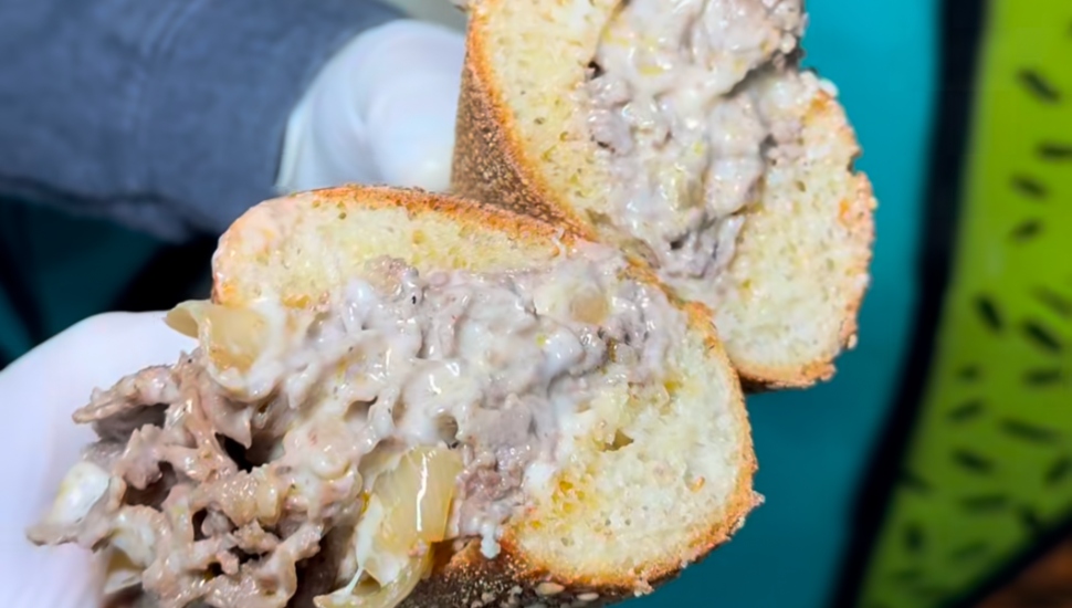 A cheesesteak being pulled apart.