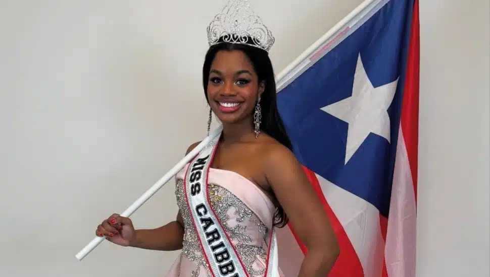 Jacqueline Means with crown, "Miss Caribbean US" sash, and a Puerto Rican flag.
