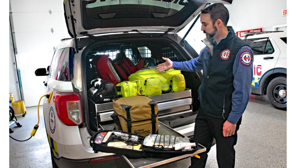 Medic 94 car parked with supplies in trunk and man examining them.