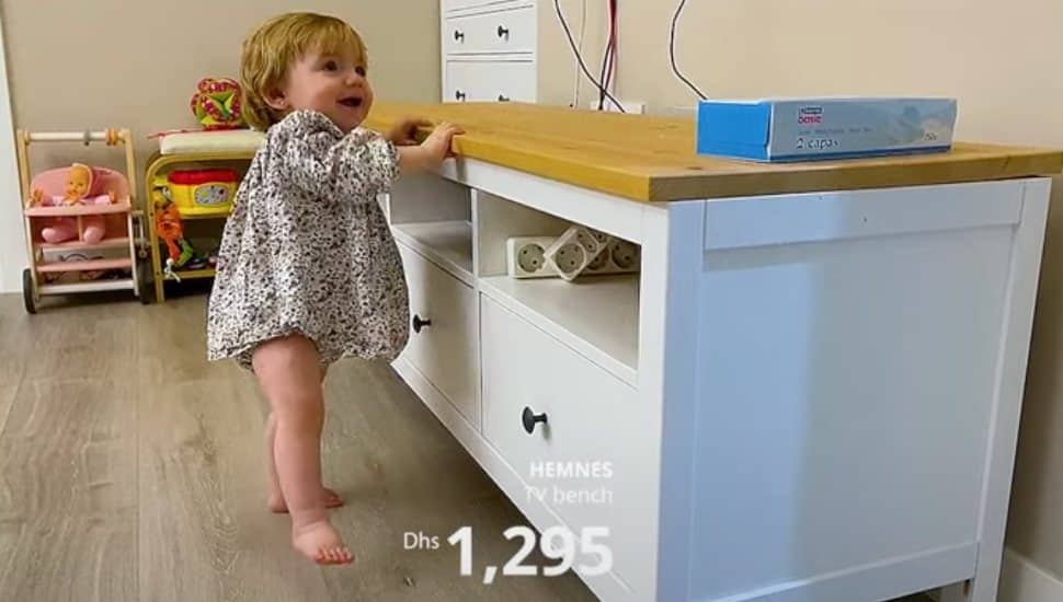 A baby using an IKEA table to help herself take first steps.