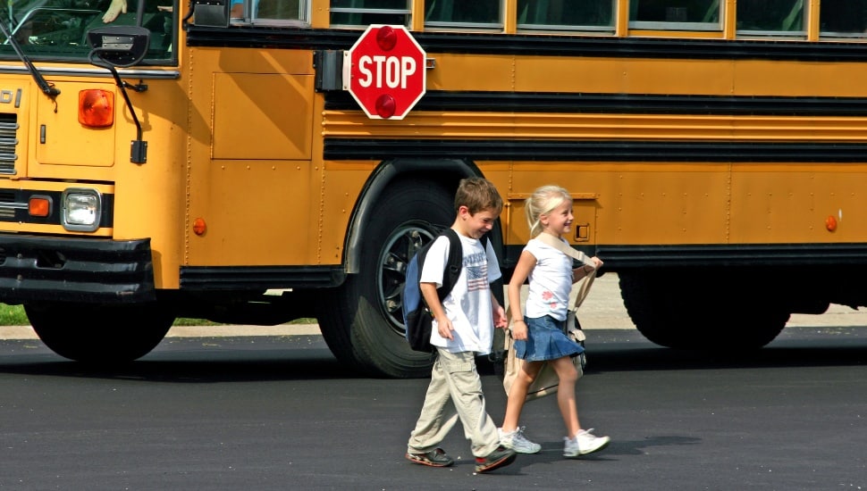 Children coming home from school after getting off a school bus.