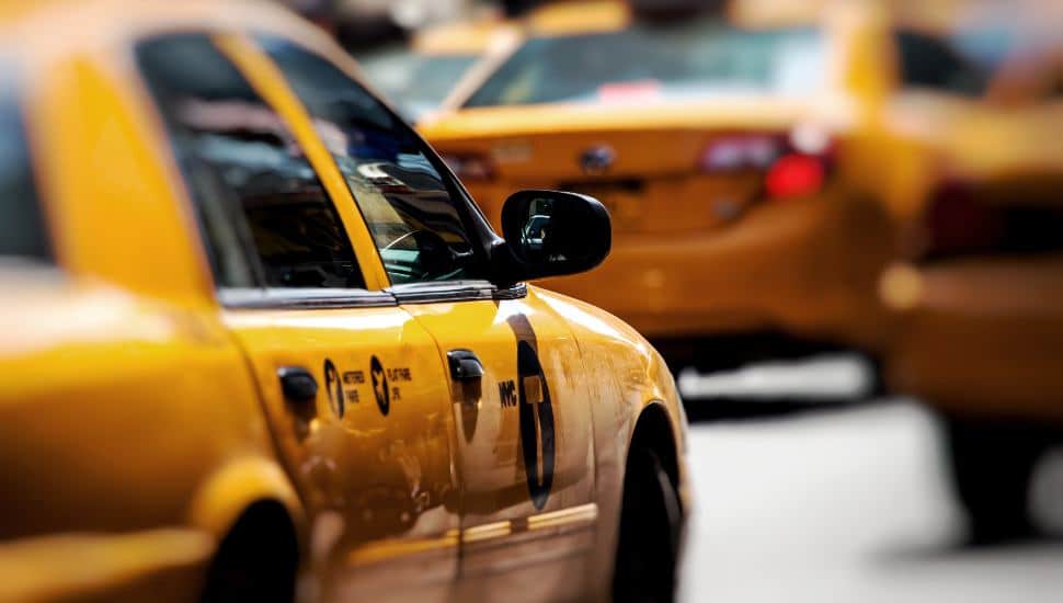 A yellow taxi cab on the road.