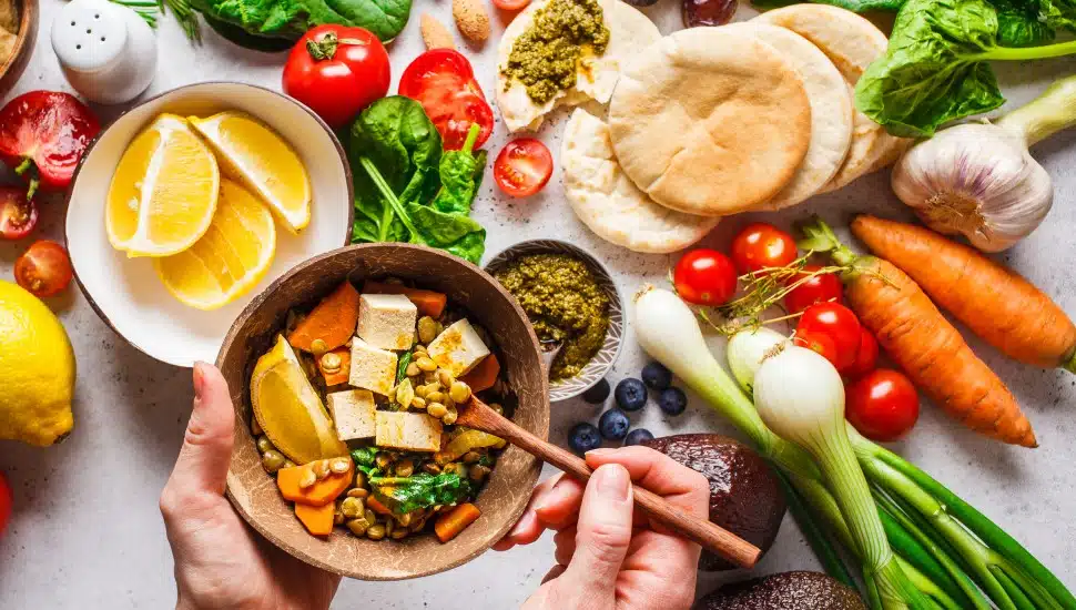 Healthy vegetarian food background with vegetables, hummus, pesto, and lentil curry with tofu.