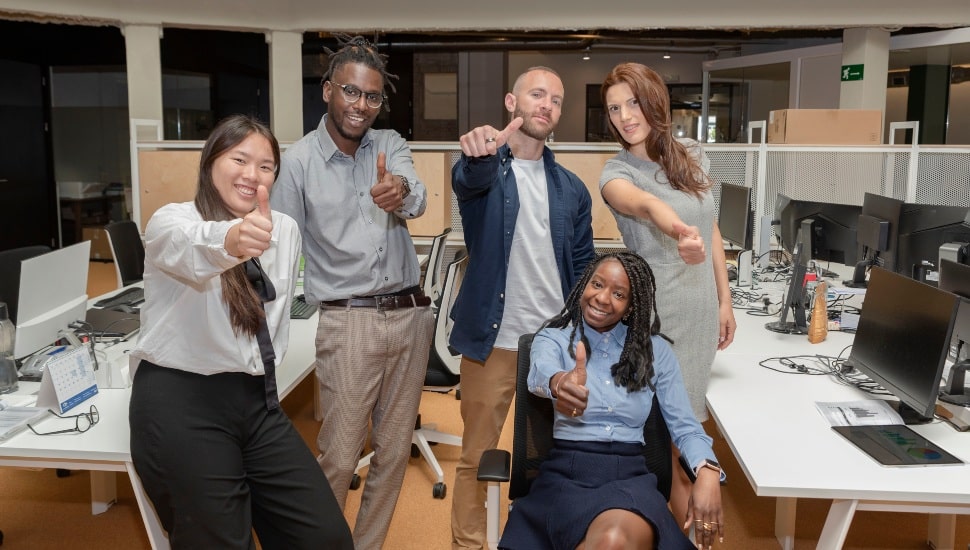 Happy multicultural business team people show thumbs up in victory sign looking at camera.