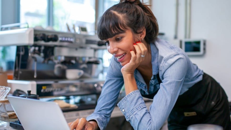 Female small business owner looks at her finances on a laptop.
