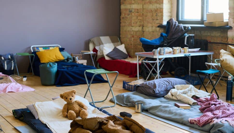 Part of spacious room with sleeping places on wooden floor for refugees or temporarily homeless people because of war or cataclysm.