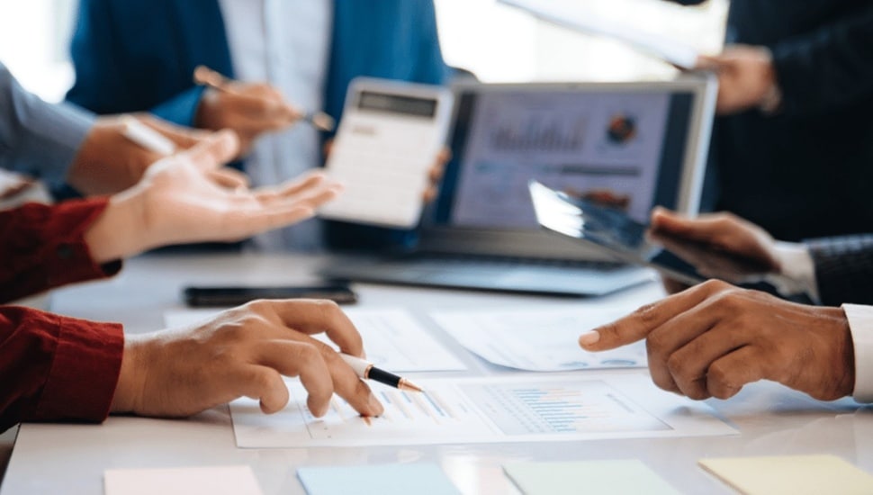 Business executives at a conference table discuss a company's valuation.