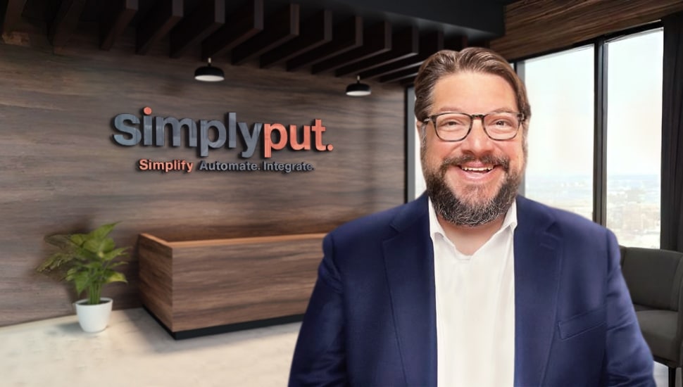 Middle-aged male CEO in blue sport coat smiles in front of company signage.