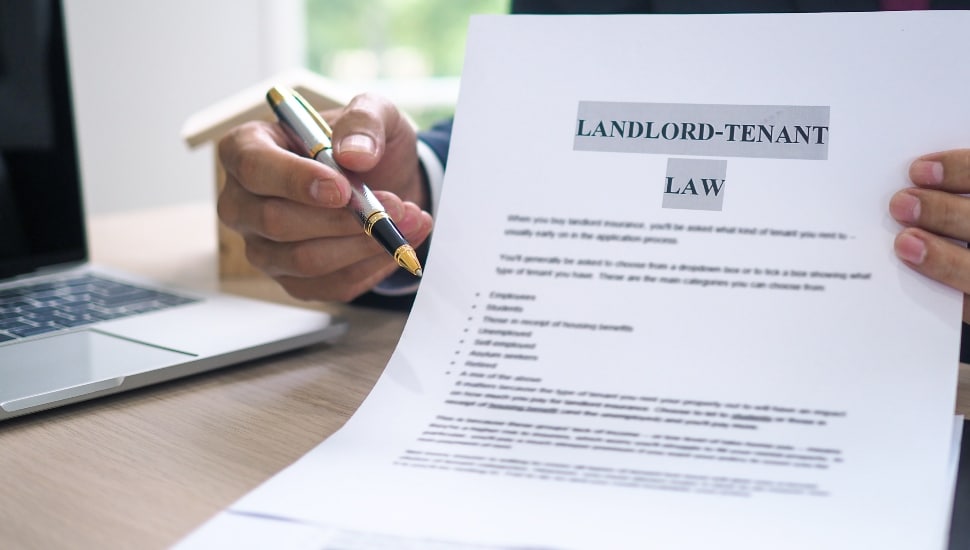 The hand of a man holding a pen and Landlord-Tenant Law document to a customer.