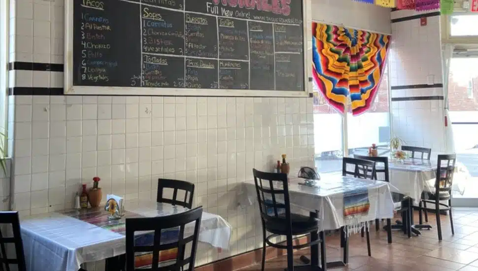 Inside Taqueria Morales restaurant with tables and chairs and a menu in the background.
