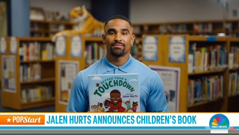 Jalen Hurts holding a copy of his new children's book.