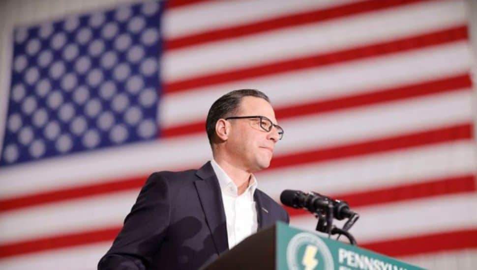 Governor Josh Shapiro speaks at a podium in front of the American Flag.