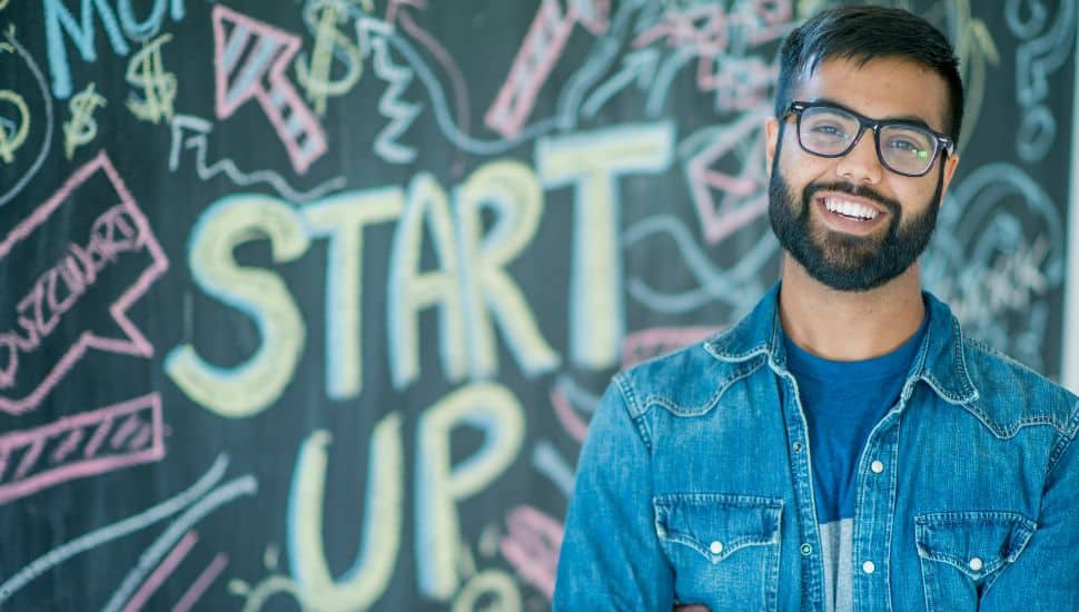 A young man in front of a start-up graphic.