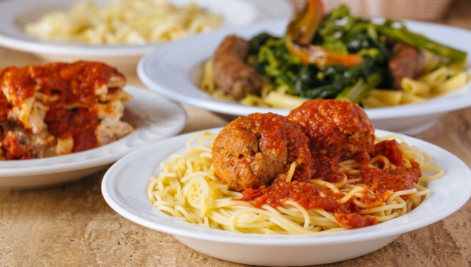 Spaghetti and meatballs in the forefront, with lasagna and pasta with vegetables, respectively, in the background.