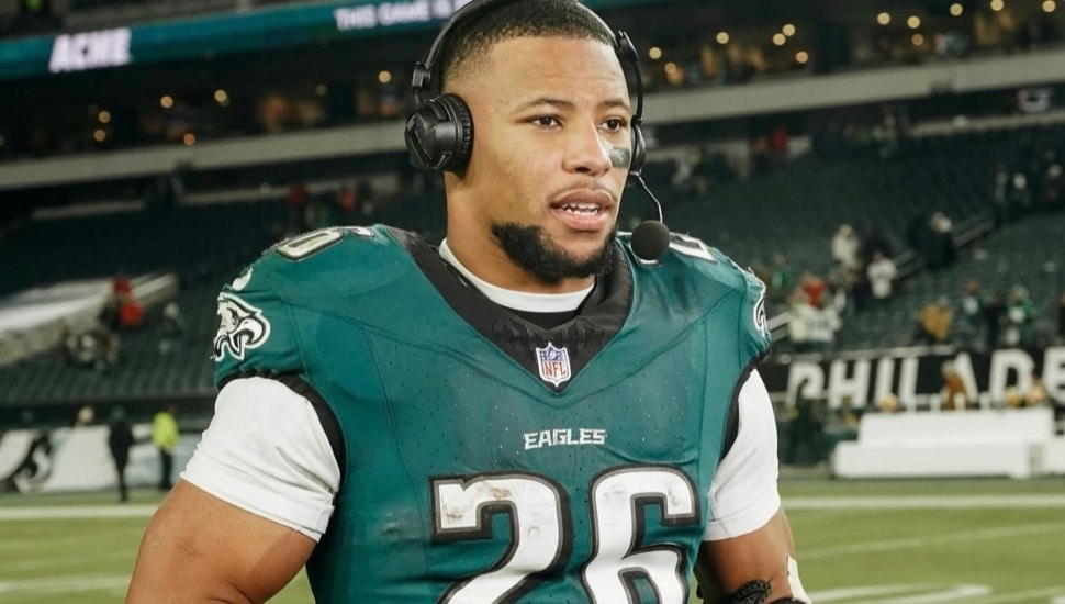 Saquon Barkley with a headset and NFC trophy after the Eagles clinched.