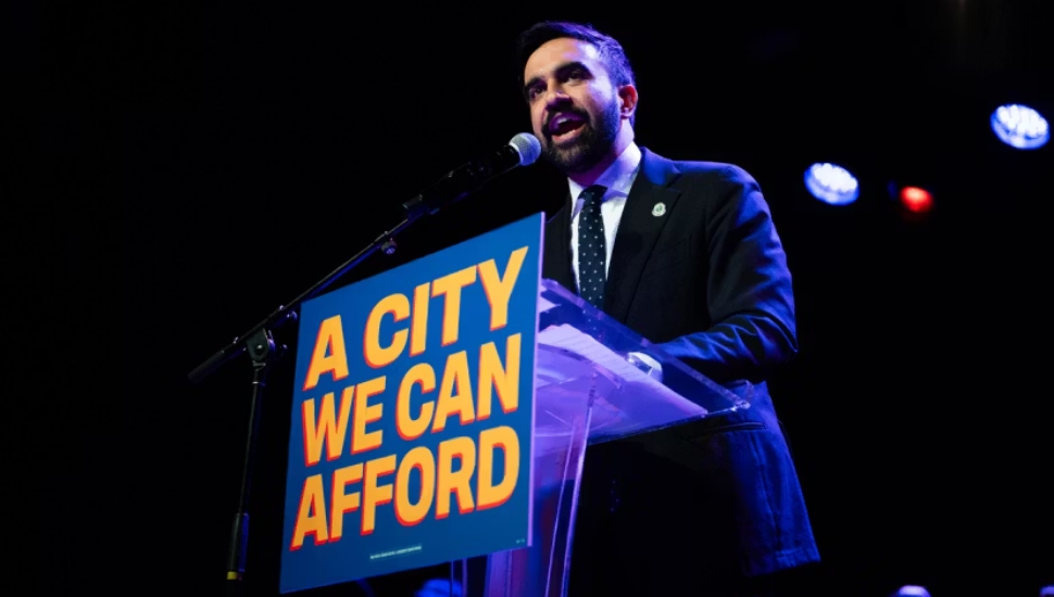 Zohran Mamdani speaking at a podium above a sign that reads "A City We Can Afford."