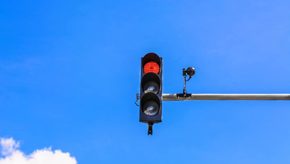 A red light camera attached to a mounted traffic light.