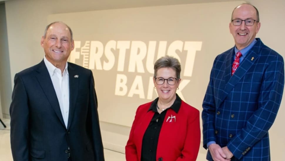 Bank's leadership team poses for a picture in front of bank signage.