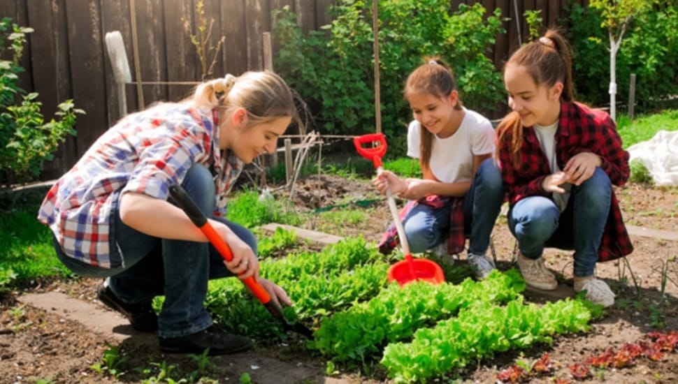 Woman works in the garden with her two daughters.