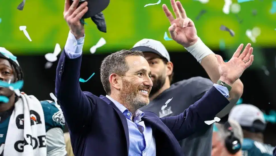 Howie Roseman celebrating the Super Bowl with confetti falling, and A.J. Brown and Dallas Goedert in the background.