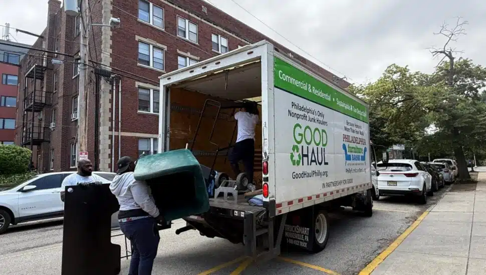 Workers picking up items and loading them into the back of a truck.